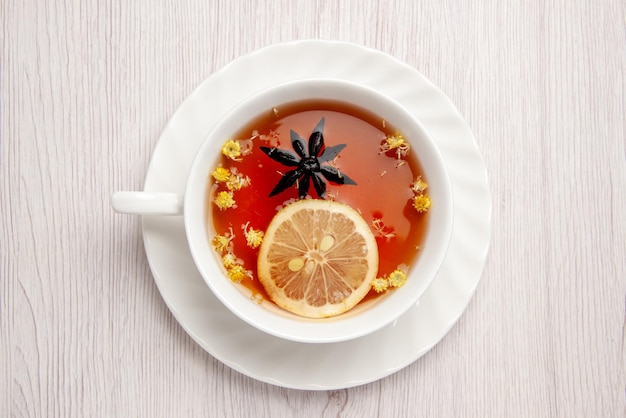 Top close-up view a cup of tea a cup of tea with slice of lemon on the white saucer on the wooden white table