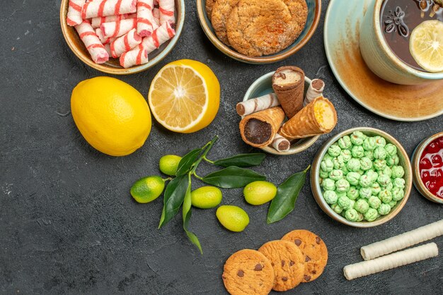 Top close-up view a cup of tea lemon citrus fruits a cup of herbal tea sweets cookies jam