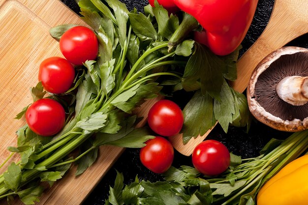 Over top close up view of different vegetables on dark table. Radish, mushrooms, green and yellow pepper on dark background