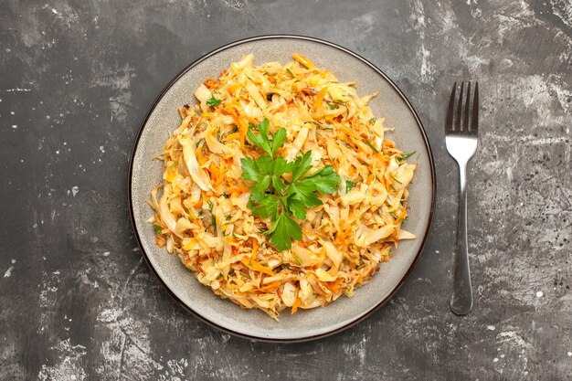 Top close-up view dish the appetizing dish of cabbage carrots herbs fork on the dark background