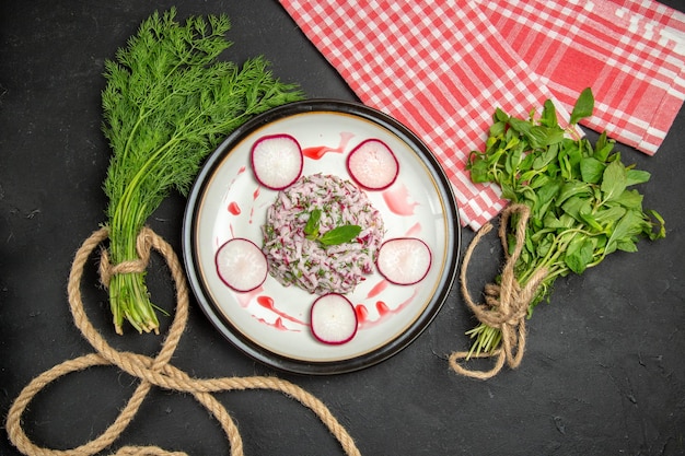 Top close-up view a dish an appetizing dish of redish greens with rope and the checkered tablecloth
