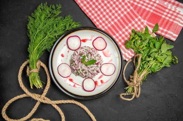 Top close-up view a dish an appetizing dish of redish greens with rope and the checkered tablecloth