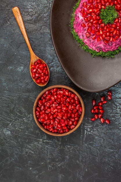 Top close-up view dish next to the bowl of pomegranate seeds spoon