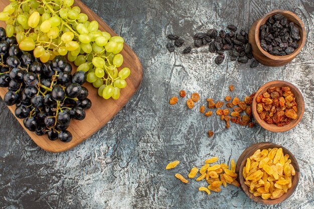Top close-up view dried fruits the appetizing grapes on the board dried fruits in the brown bowls