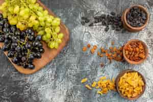 Бесплатное фото Сверху крупным планом сушеные фрукты аппетитный виноград на доске сухофрукты в коричневых мисках