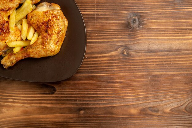 나무 탁자에 있는 갈색 접시에 있는 맛있는 감자튀김과 닭고기를 가장 가까이에서 볼 수 있는 패스트푸드