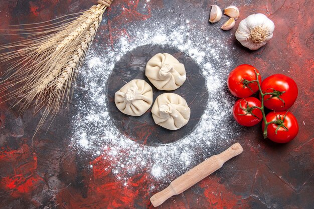 Top close-up view flour flour three khinkali tomatoes garlic rolling pin