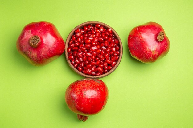 Top close-up view fruits the appetizing apples and seeds of pomegranate on the green surface