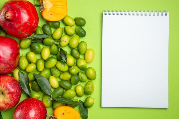 Top close-up view fruits apples pomegranates citrus fruits persimmons and white notebook