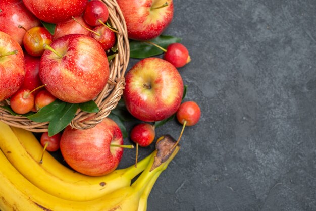 Top close-up view fruits basket of cherries apples bananas