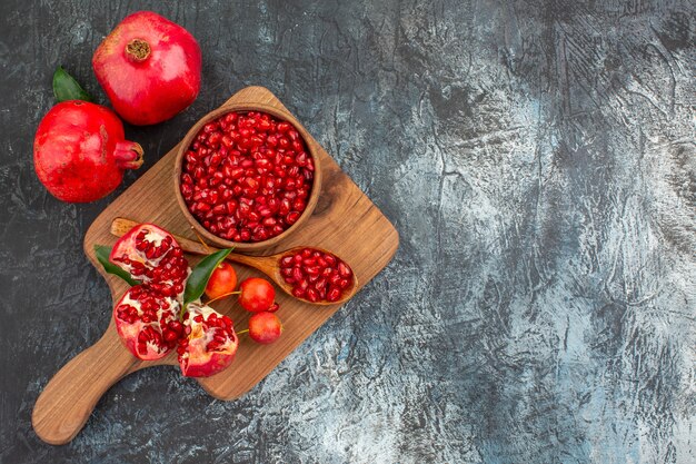 Top close-up view fruits the board with pomegranate seeds spoon peeled pomegranate cherries