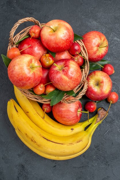 Top close-up view fruits cherries apples in the basket bananas