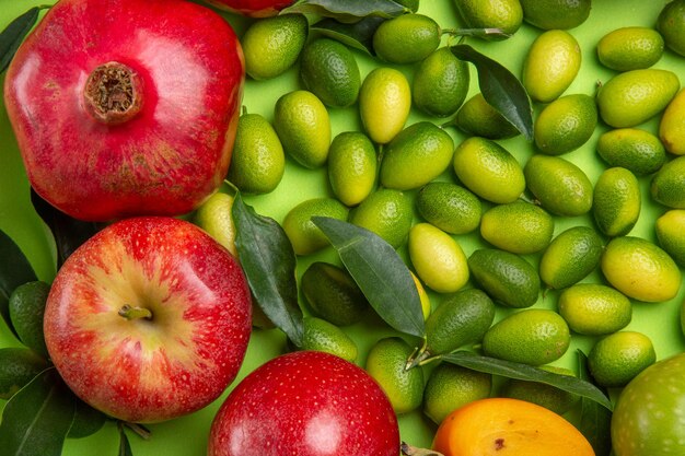 Top close-up view fruits citrus fruits pomegranates apples on the green table