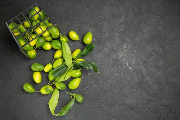 Free photo top close-up view fruits citrus fruits with leaves next to the basket with fruits on the table