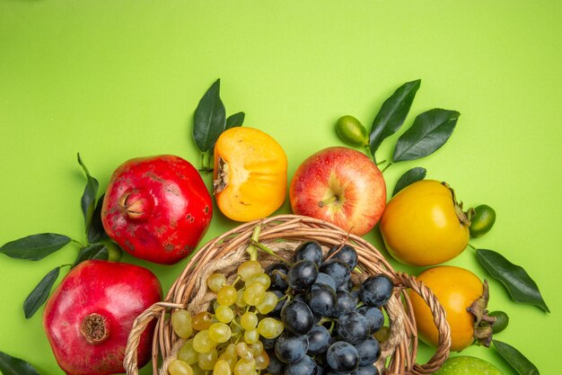 Top close-up view fruits persimmons apples basket of bunches of grapes leaves