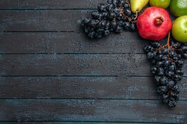 어두운 탁자의 오른쪽에 있는 과일 석류 사과 배 라임과 포도