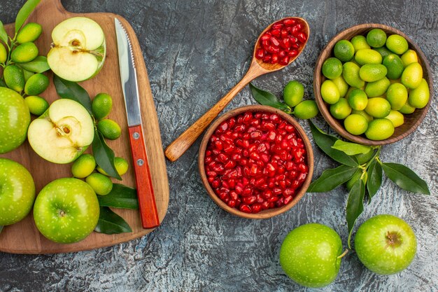 Top close-up view fruits pomegranate spoon apples citrus fruits apples knife on the board