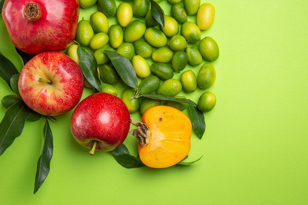 Вид сверху крупным планом фрукты гранаты яблоки зеленые цитрусовые фрукты хурма на столе