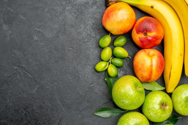 Top close-up view fruits on the table limes green apples with leaves yellow bananas and nectarines