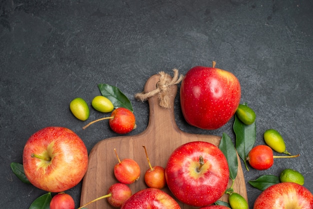 Top close-up view fruits yellow-red berries apples on the board citrus fruits