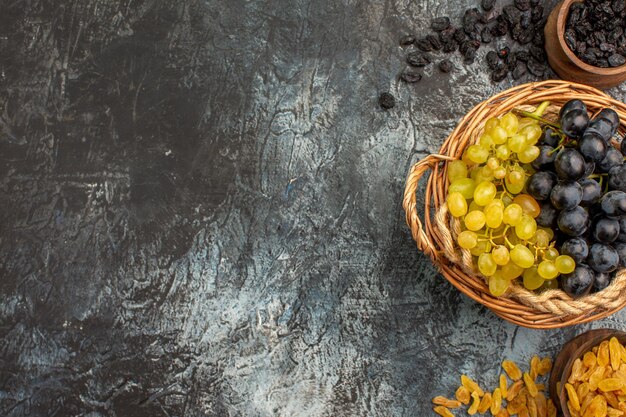 Free photo top close-up view grapes the appetizing grapes between bowls of dried fruits on the right side