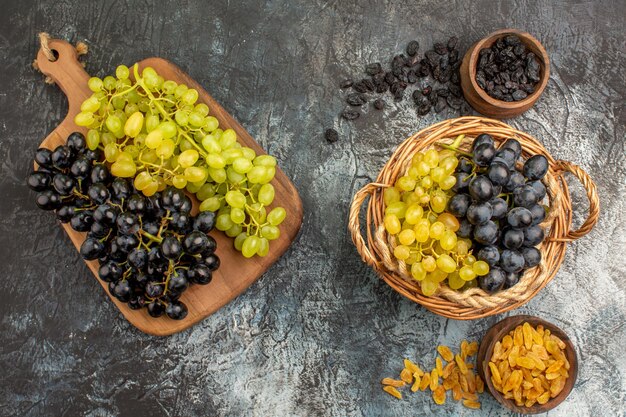Foto gratuita vista ravvicinata dall'alto cesto d'uva e tagliere d'uva tra e due ciotole di frutta secca