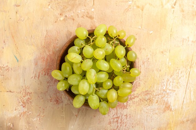 Top close-up view grapes bowl of bunches of green grapes on the cream table