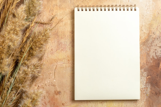 Free photo top close-up view notebook white notebook next to the spikelets on the table