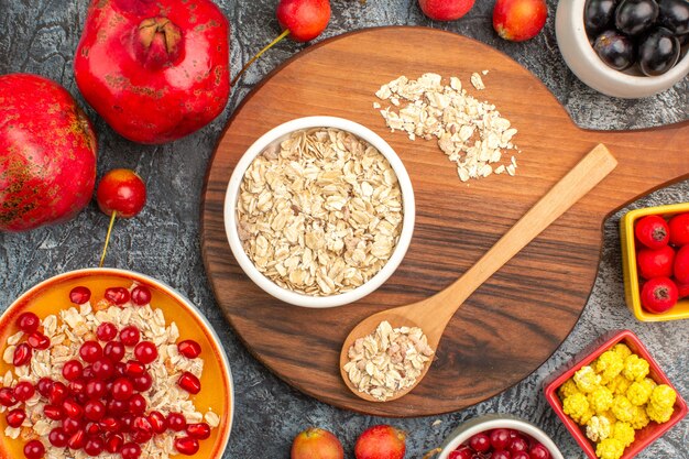 Top close-up view oatmeal the appetizing pomegranates colorful berries oatmeal spoon on the board