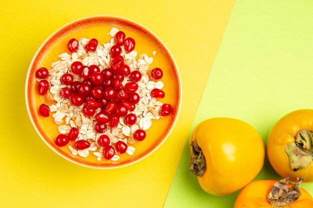 Top close-up view oatmeal oatmeal with red currants pomegranates in the bowl persimmons