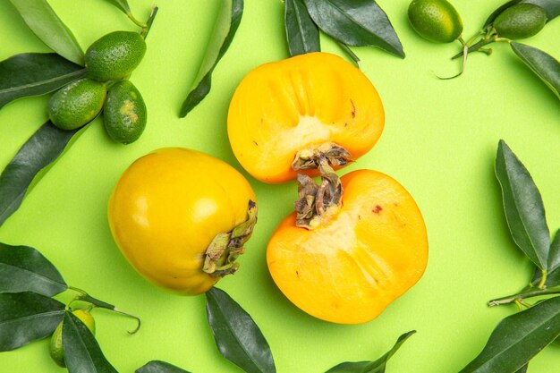 Top close-up view persimmon persimmons and citrus fruits with green leaves