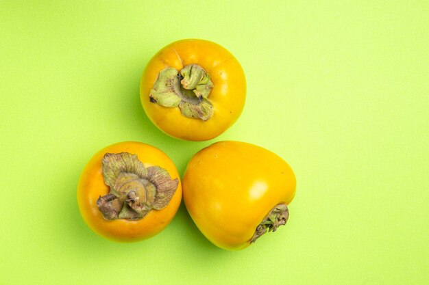 Top close-up view persimmons three appetizing persimmons on the green table