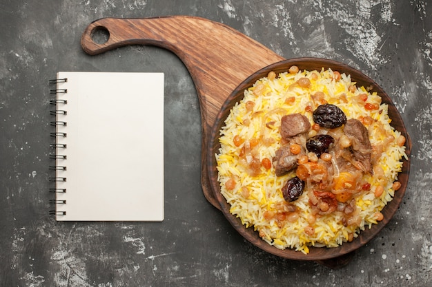 Free photo top close-up view pilaf an appetizing pilaf on the wooden cutting board notebook