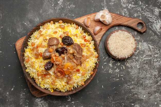 Top close-up view pilaf an appetizing pilaf on the wooden kitchen board garlic bowl of rice