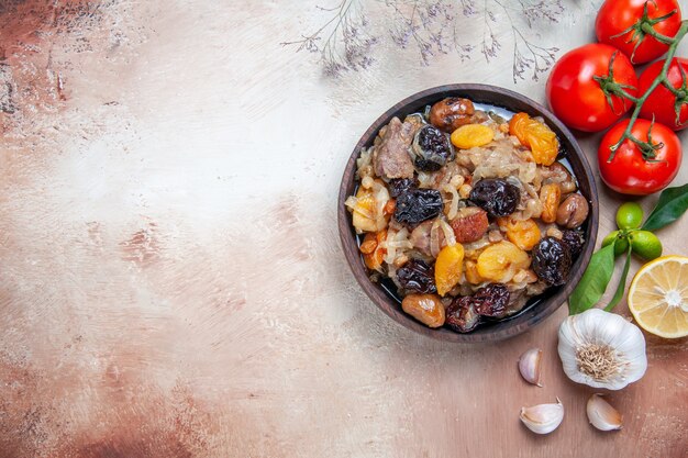 Top close-up view pilaf bowl of rice chestnuts dried fruits tomatoes garlic lemon