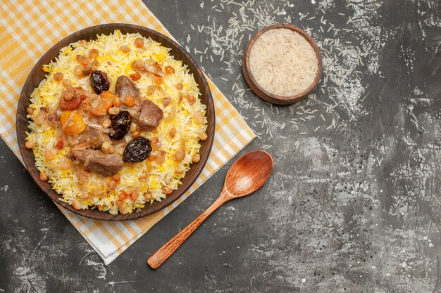 Top close-up view pilaf bowl of rice spoon an appetizing pilaf on the checkered tablecloth