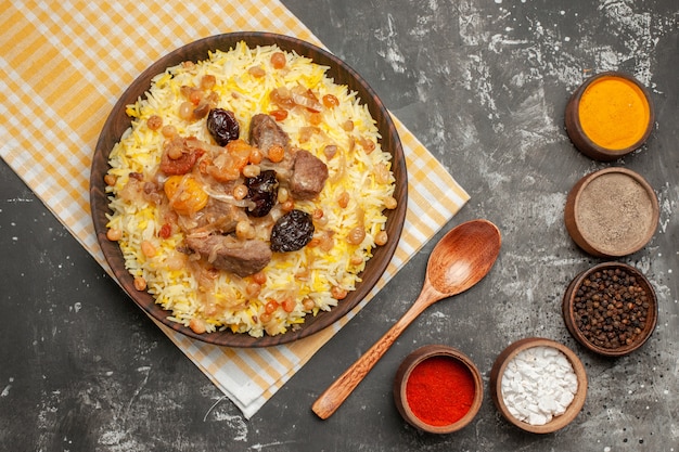 Top close-up view pilaf colorful spices spoon an appetizing pilaf on the checkered tablecloth