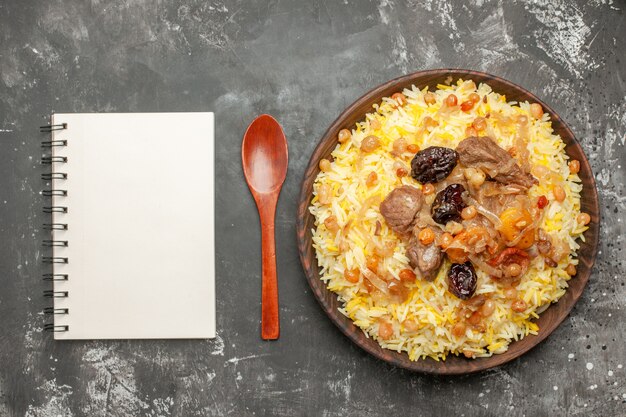 쌀 고기와 말린 과일 노트북의 상위 클로즈업보기 필라프 숟가락 그릇