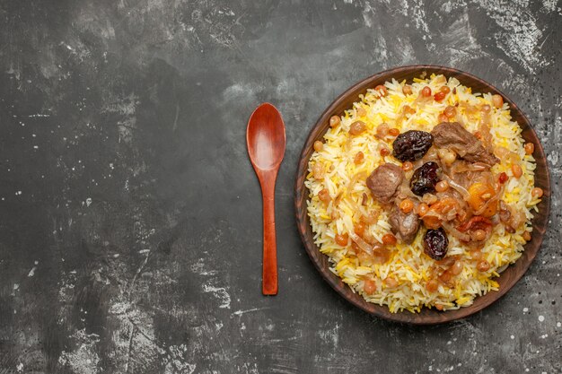 Top close-up view pilaf spoon bowl of rice meat and dried fruits