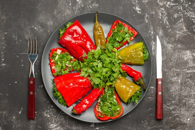 Top close-up view plate of peppers plate of colorful peppers with herbs between fork and knife