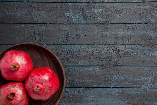 Top close-up view plate of pomegranates plate of ripe red pomegranates on the left side of table