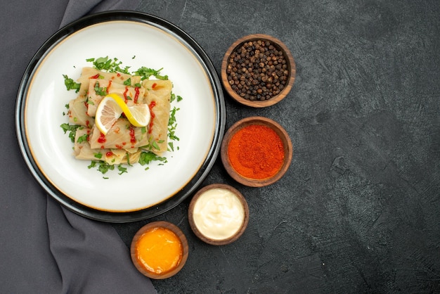 Top close-up view plate and tablecloth white plate of stuffed cabbage with herbs lemon and sauce