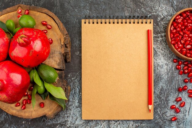 Top close-up view pomegranate notebook pencil seeds of pomegranate pomegranates on the board