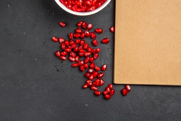 Top close-up view pomegranate pomegranate seeds in the bowl cream notebook