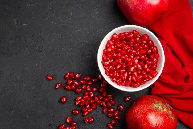 Top close-up view pomegranate two pomegranates pomegranate seeds in the bowl red tablecloth