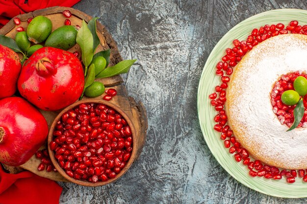 Top close-up view pomegranates an appetizing cake and red pomegranates on the red tablecloth