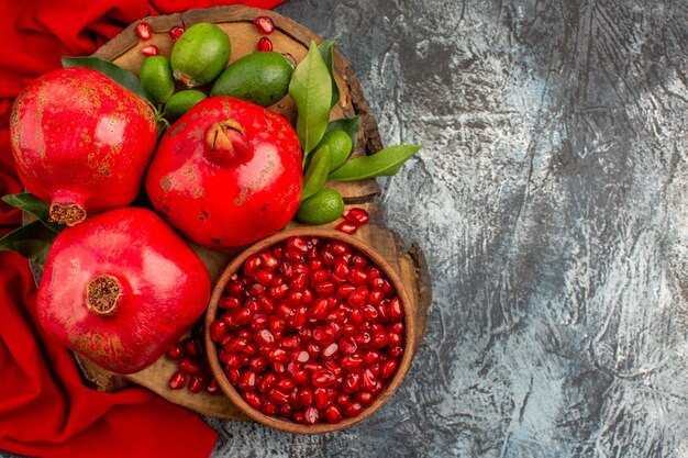 Top close-up view pomegranates pomegranate and pomegranate seeds on the board on the red tablecloth