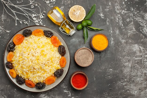 Top close-up view rice bottle of oil citrus fruits plate of rice with dried fruits spices