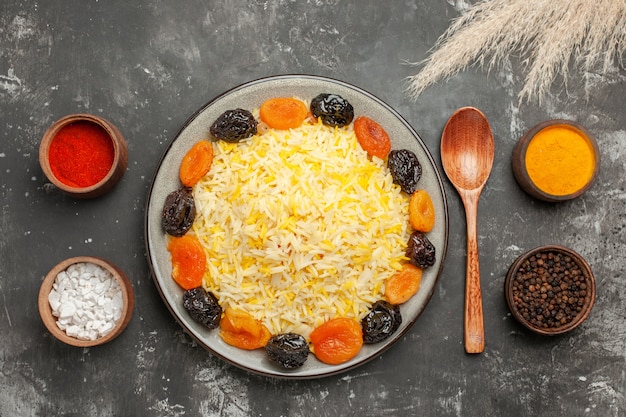 Free photo top close-up view rice bowls of colorful spices spoon plate of rice with dried fruits