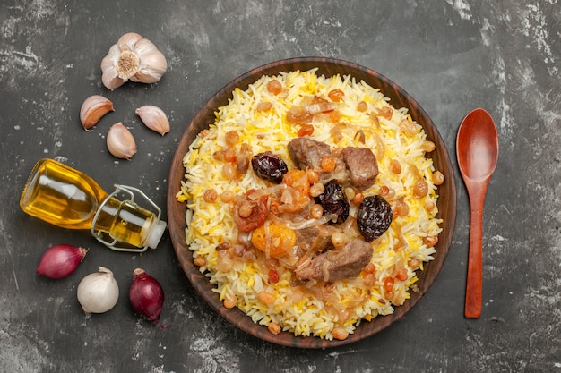 Top close-up view rice onion garlic bottle of oil spoon an appetizing pilaf